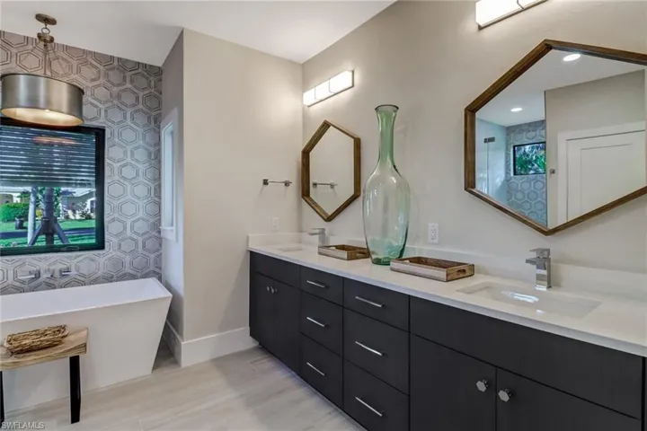 Full bathroom with double vanity, a freestanding bath, and light wood-type flooring