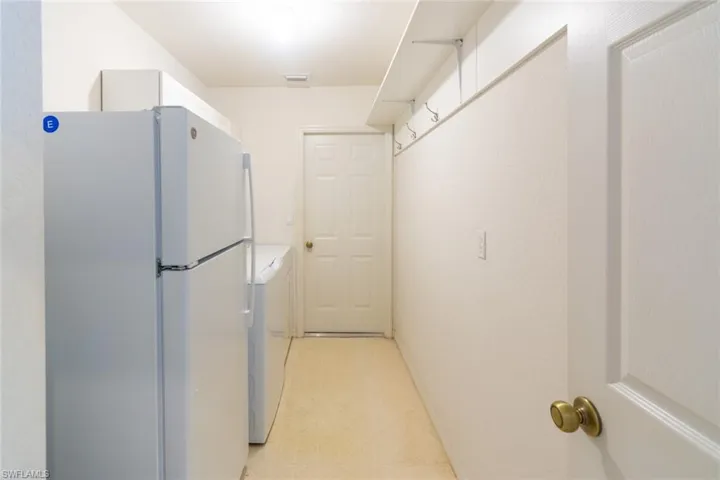 Kitchen featuring washer and clothes dryer, white fridge, and light tile patterned floors