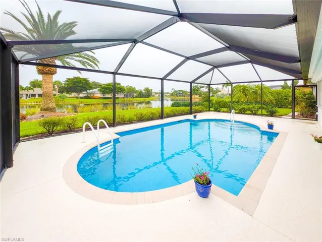 View of swimming pool featuring a water view, glass enclosure, and a patio area