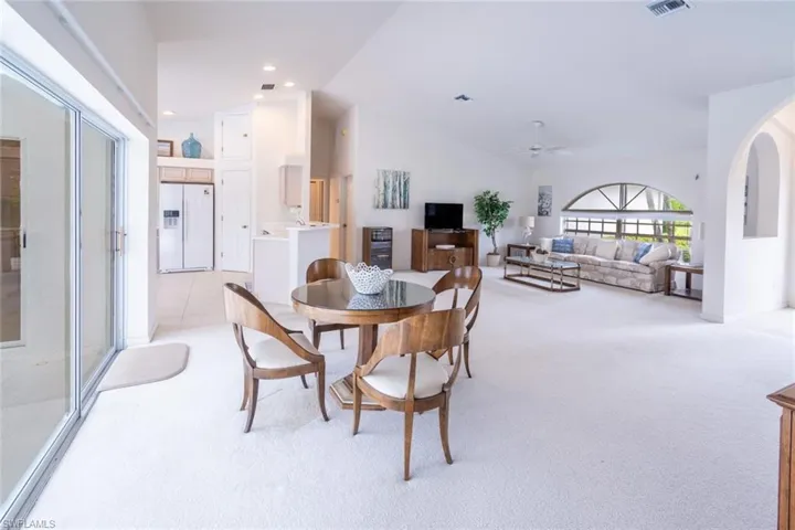 Dining space featuring light carpet, ceiling fan, and vaulted ceiling