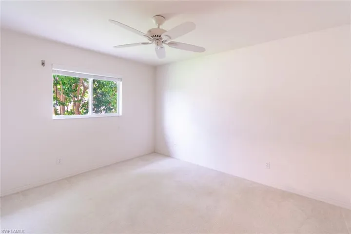 Carpeted empty room featuring ceiling fan
