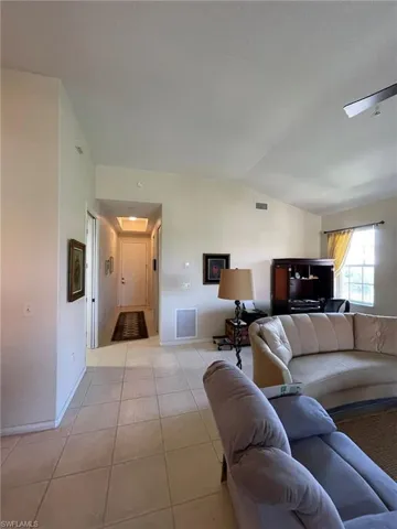 Living room featuring light tile flooring and vaulted ceiling