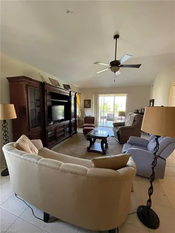 Living room featuring vaulted ceiling, ceiling fan, and light tile floors