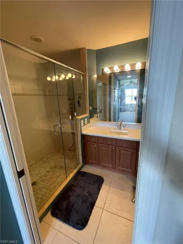 Bathroom with tile floors, an enclosed shower, and vanity