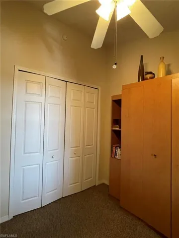 Second bedroom with dark colored carpet ,ceiling fan and Murphy Bed.