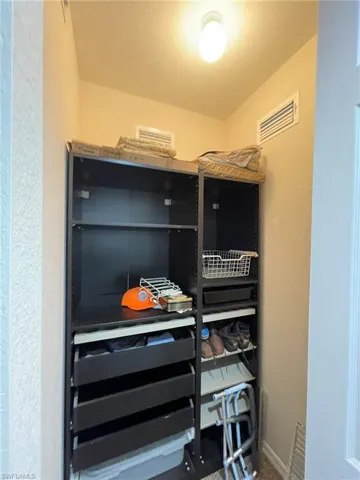 One of two master walk-in closets featuring carpet flooring with custom shelving.