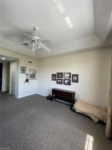 Carpeted master bedroom with ceiling fan and a tray ceiling