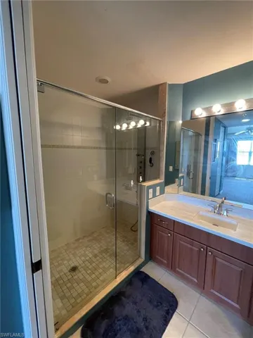 Bathroom with a shower with door, tile flooring, and vanity