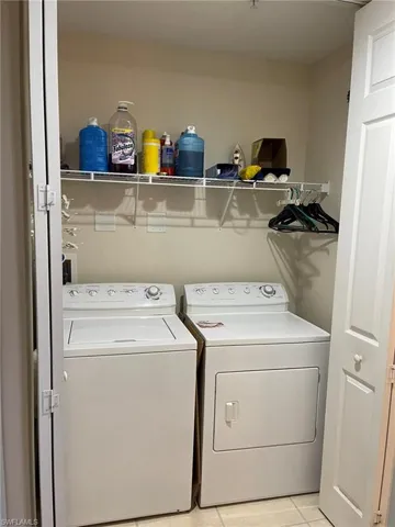 Laundry area with light tile flooring and washer and clothes dryer