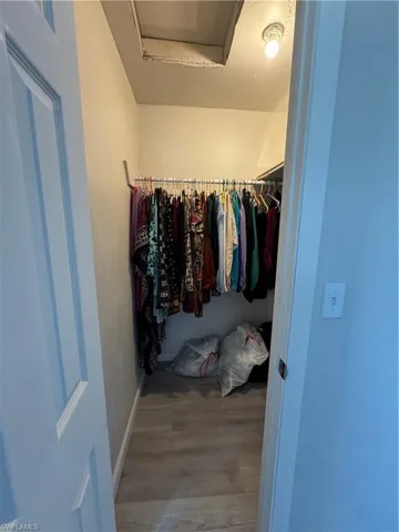 Walk in closet with hardwood / wood-style floors