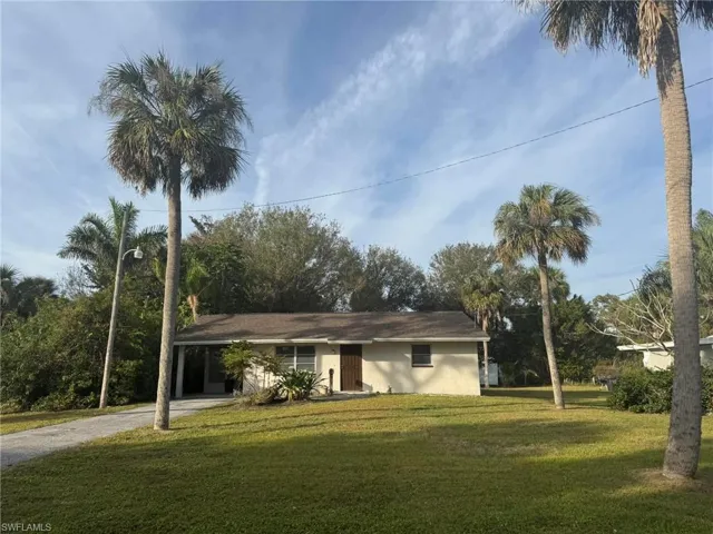 Ranch-style home featuring a carport and a front lawn