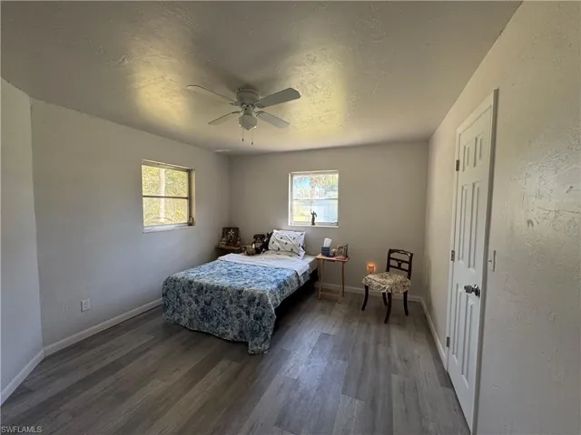 Bedroom featuring multiple windows, wood-type flooring, a textured ceiling, and ceiling fan