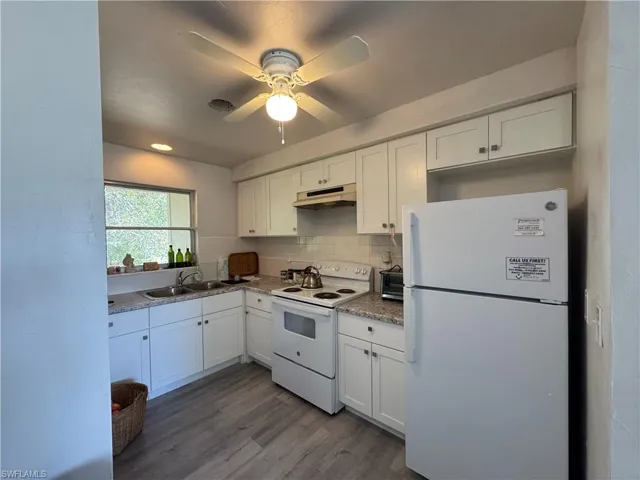 Kitchen with sink, white cabinets, decorative backsplash, light hardwood / wood-style floors, and white appliances