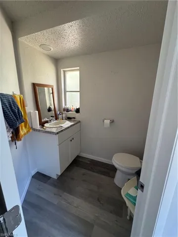 Bathroom featuring hardwood / wood-style flooring, vanity, a textured ceiling, and toilet