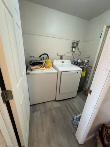 Washroom with water heater, hardwood / wood-style flooring, and independent washer and dryer
