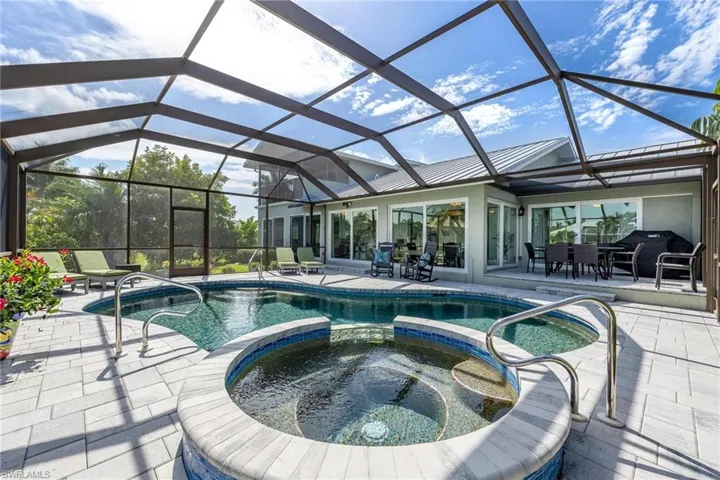 View of swimming pool with an in ground hot tub, a patio, and a lanai