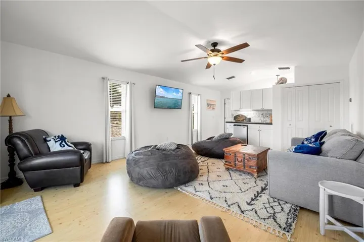 Living room featuring ceiling fan, light hardwood / wood-style flooring, and lofted ceiling