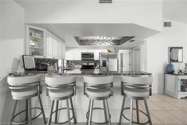 Kitchen with kitchen peninsula, stainless steel appliances, white cabinets, and tasteful backsplash