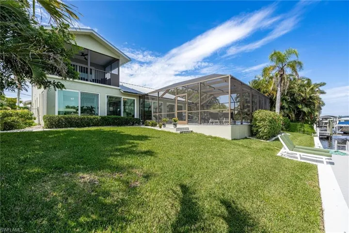 View of yard with ceiling fan, a balcony, and glass enclosure