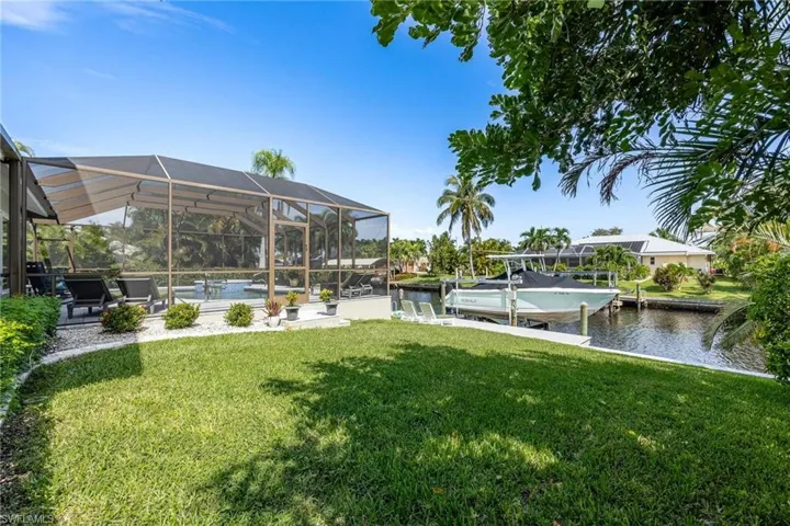 View of yard with glass enclosure, a boat dock, and a water view