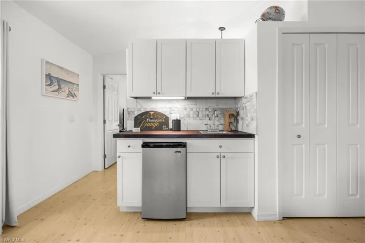 Kitchen with decorative backsplash, stainless steel dishwasher, light hardwood / wood-style flooring, wood counters, and sink