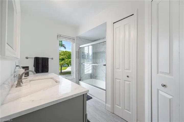 Bathroom featuring shower / bath combination with glass door and vanity