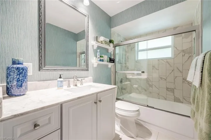 Full bathroom featuring tile patterned flooring, bath / shower combo with glass door, toilet, and vanity