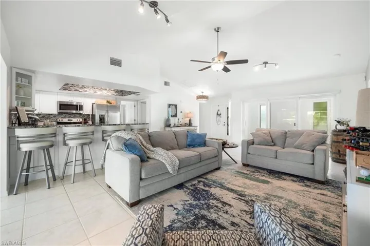 Tiled living room featuring high vaulted ceiling, ceiling fan, and rail lighting