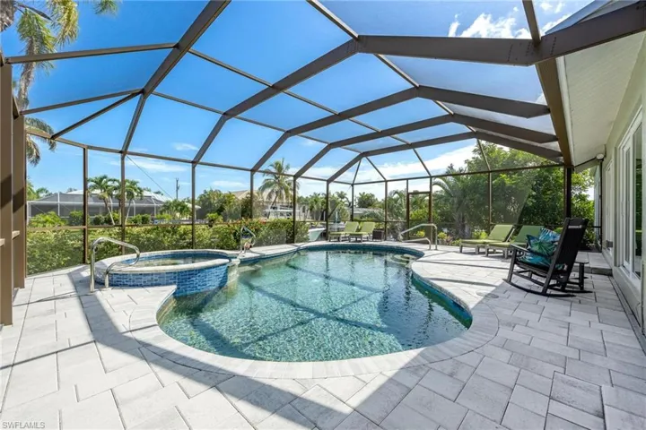 View of swimming pool featuring a patio area, an in ground hot tub, and a lanai