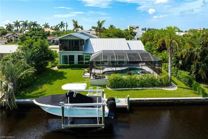 Rear view of property with a yard, a water view, and a lanai