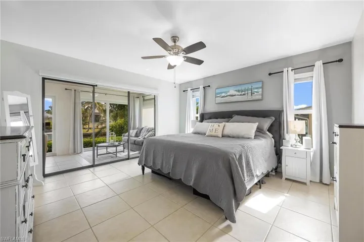 Bedroom featuring ceiling fan, access to outside, light tile patterned floors, and multiple windows