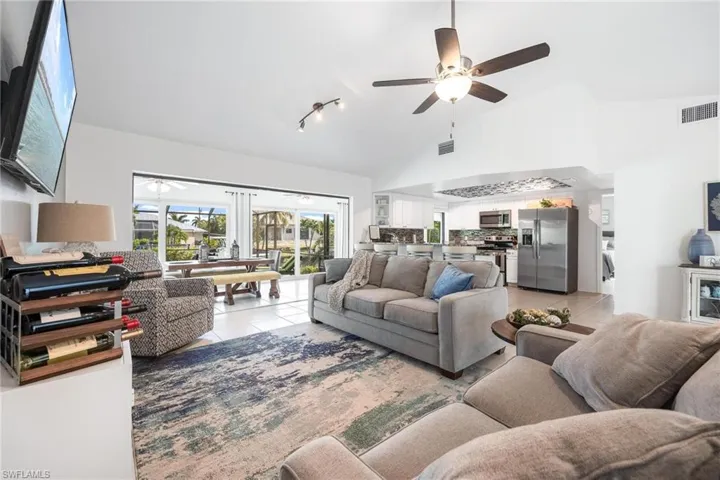 Tiled living room with ceiling fan, high vaulted ceiling, and track lighting