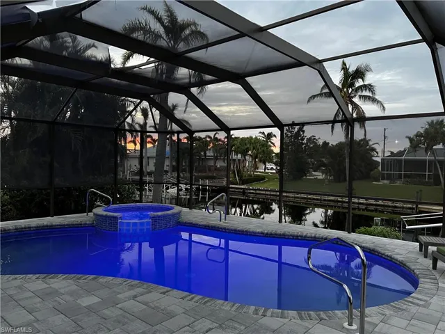 View of swimming pool featuring an in ground hot tub, a patio, and a lanai