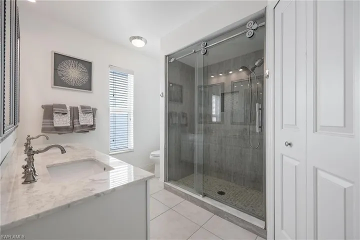Bathroom featuring tile patterned flooring, toilet, an enclosed shower, and vanity