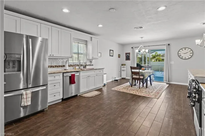 Kitchen with appliances with stainless steel finishes, plenty of natural light, white cabinetry, and backsplash
