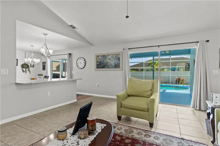 Tiled living room with a notable chandelier, lofted ceiling, and a healthy amount of sunlight