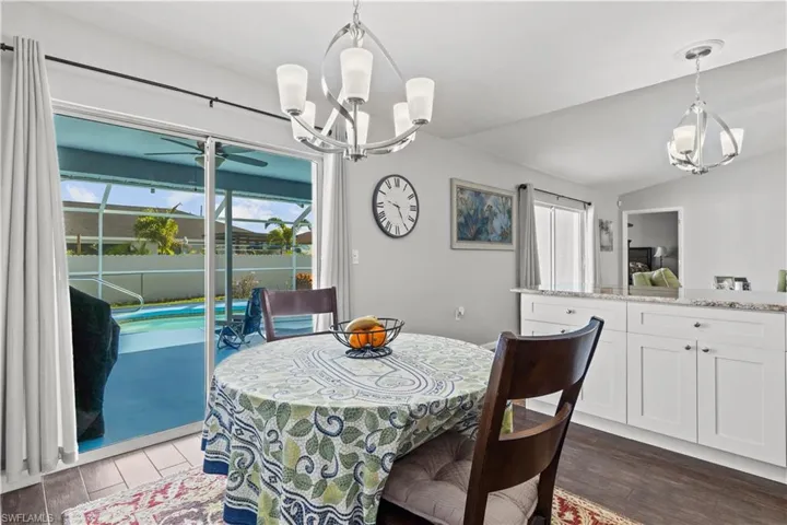 Dining space with vaulted ceiling, ceiling fan with notable chandelier, and hardwood / wood-style floors