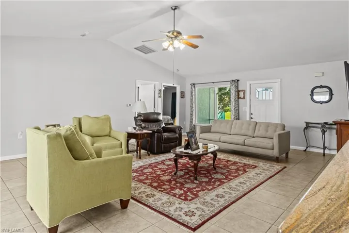 Tiled living room with ceiling fan and lofted ceiling