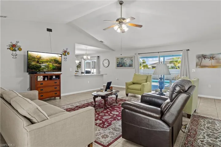Tiled living room with high vaulted ceiling and ceiling fan with notable chandelier