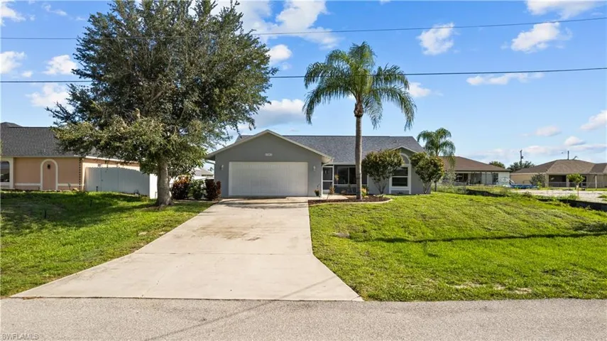 Ranch-style house featuring a garage and a front lawn