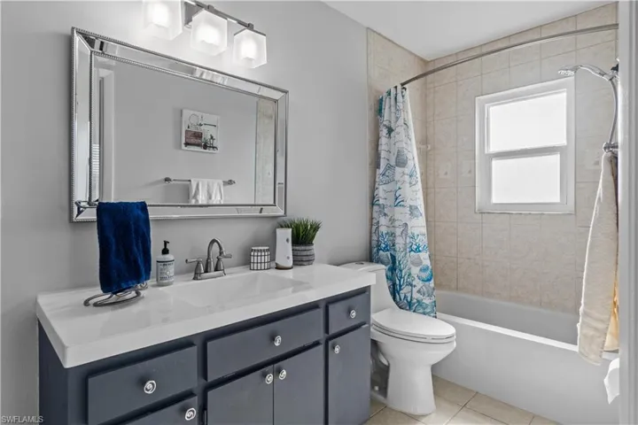 Full bathroom with toilet, vanity, shower / tub combo, and tile patterned floors