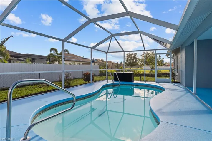 View of pool with glass enclosure and a patio