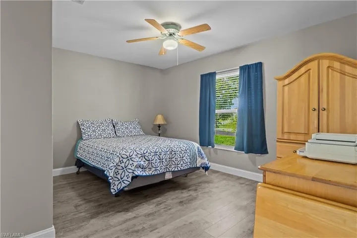 Bedroom with ceiling fan, multiple windows, and wood-type flooring