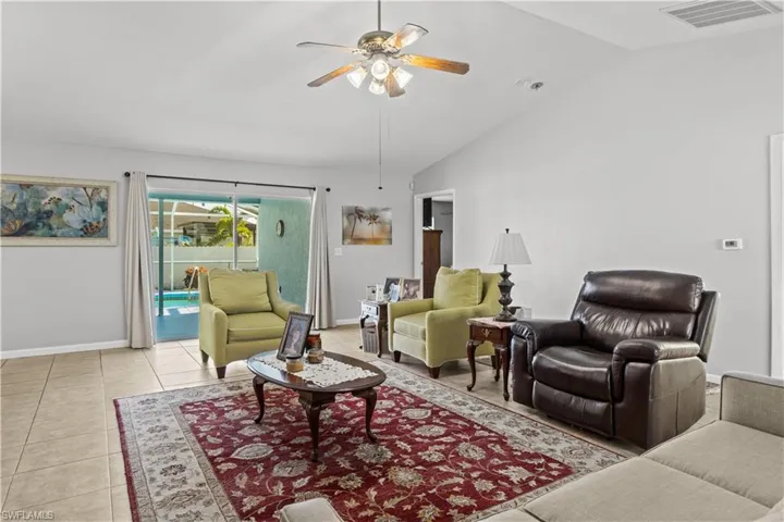 Tiled living room with ceiling fan and high vaulted ceiling