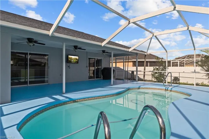 View of swimming pool with ceiling fan, a patio, and a lanai