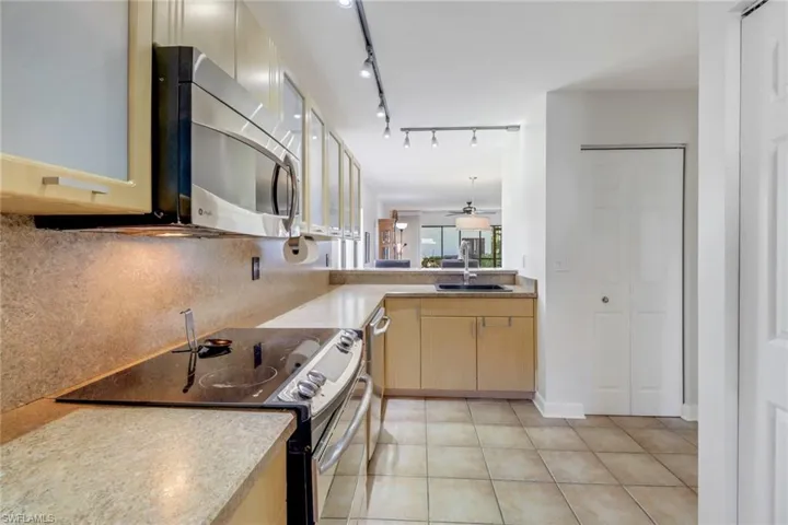 Kitchen with decorative backsplash, black stove, light tile patterned floors, and sink