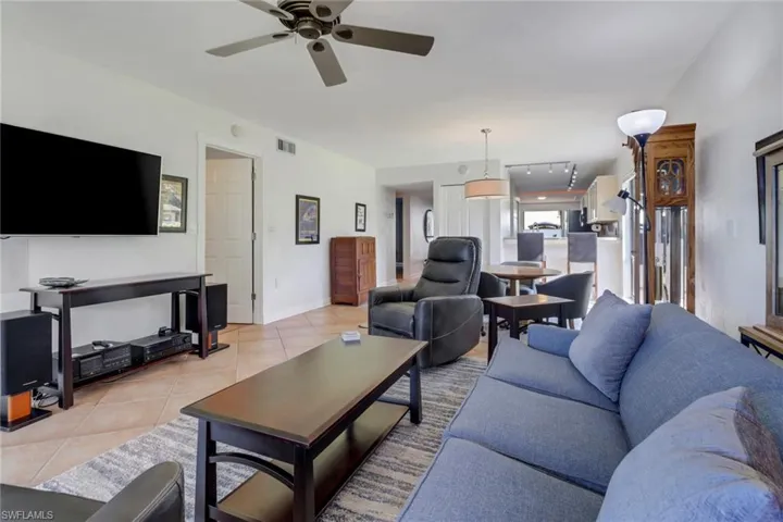 Living room with ceiling fan and light tile patterned flooring