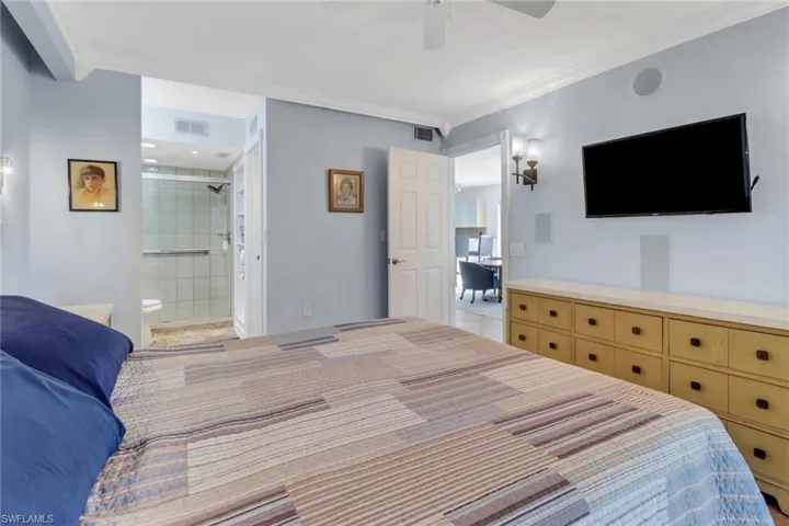 Bedroom with ensuite bathroom, crown molding, and ceiling fan
