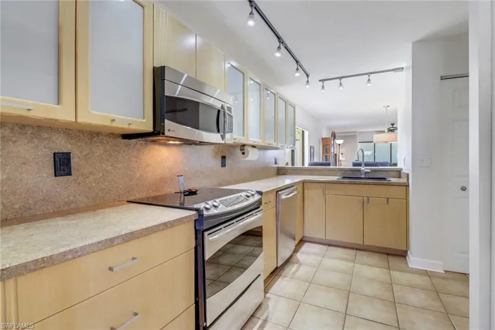 Kitchen with tasteful backsplash, stainless steel appliances, sink, light brown cabinets, and light tile patterned floors