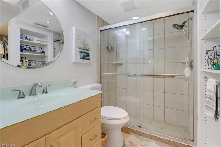 Bathroom featuring tile patterned flooring, vanity, toilet, and a shower with door